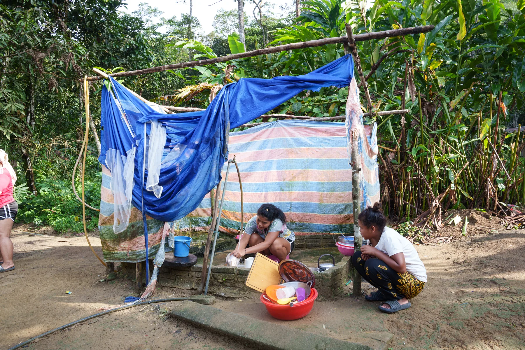 A family preparing food beside a simple shelter in the village