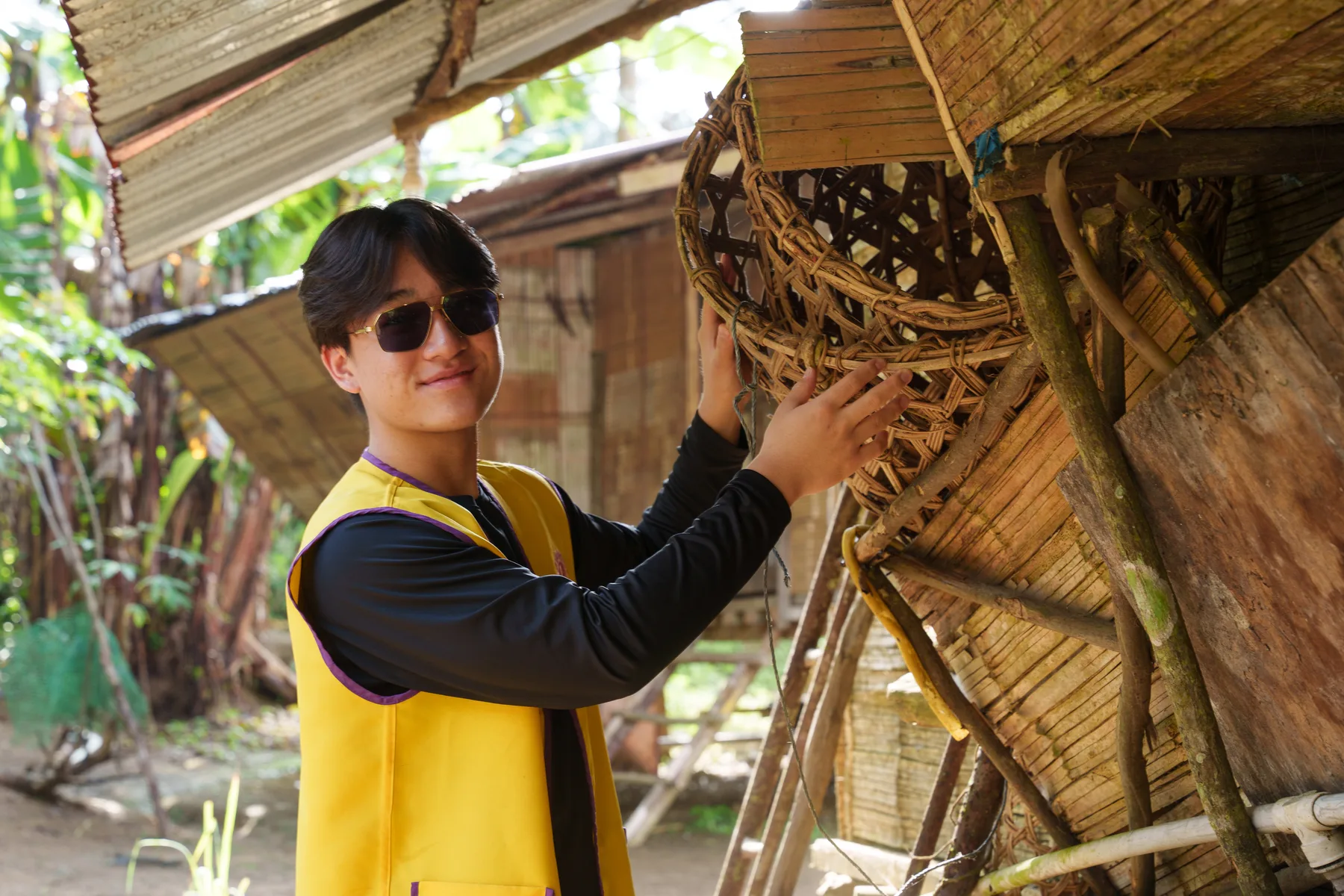 Louie examining the woven wall of a traditional village home