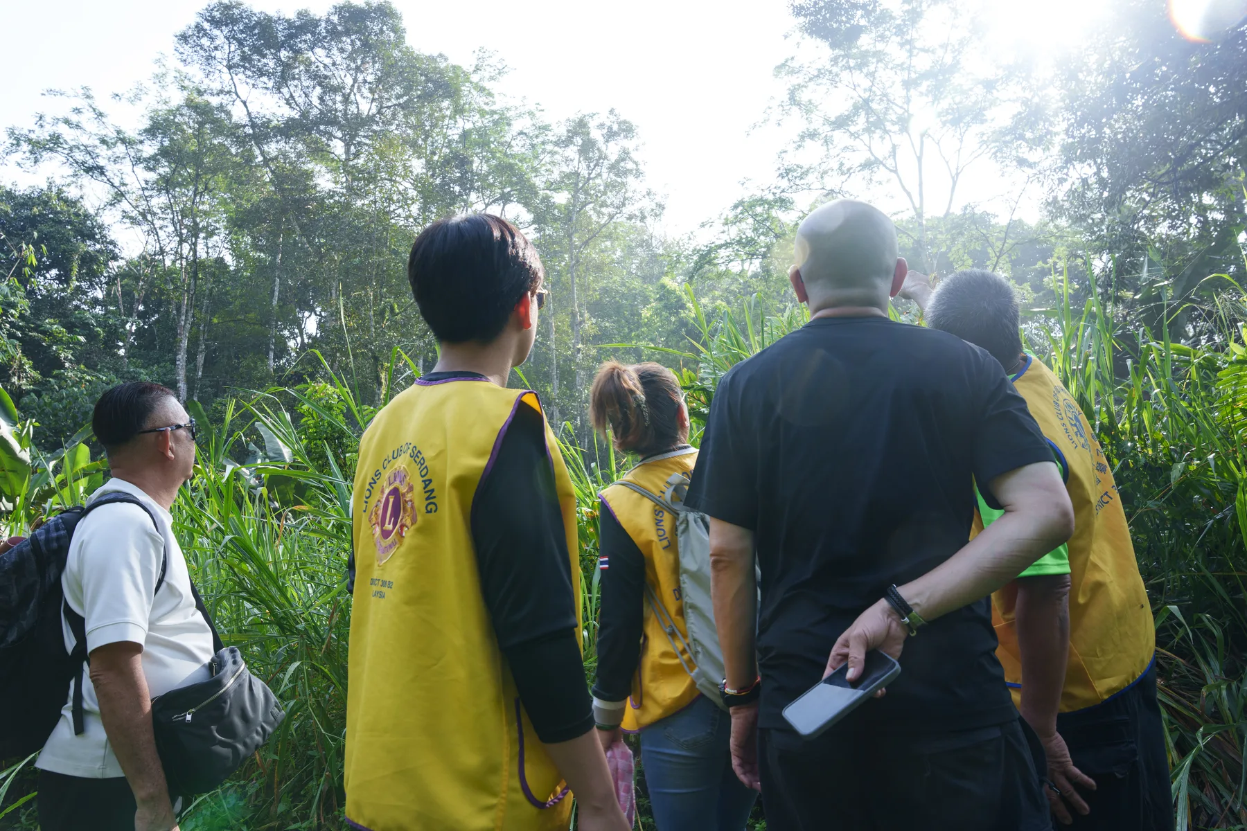 Louie and volunteers walking through dense greenery toward the village