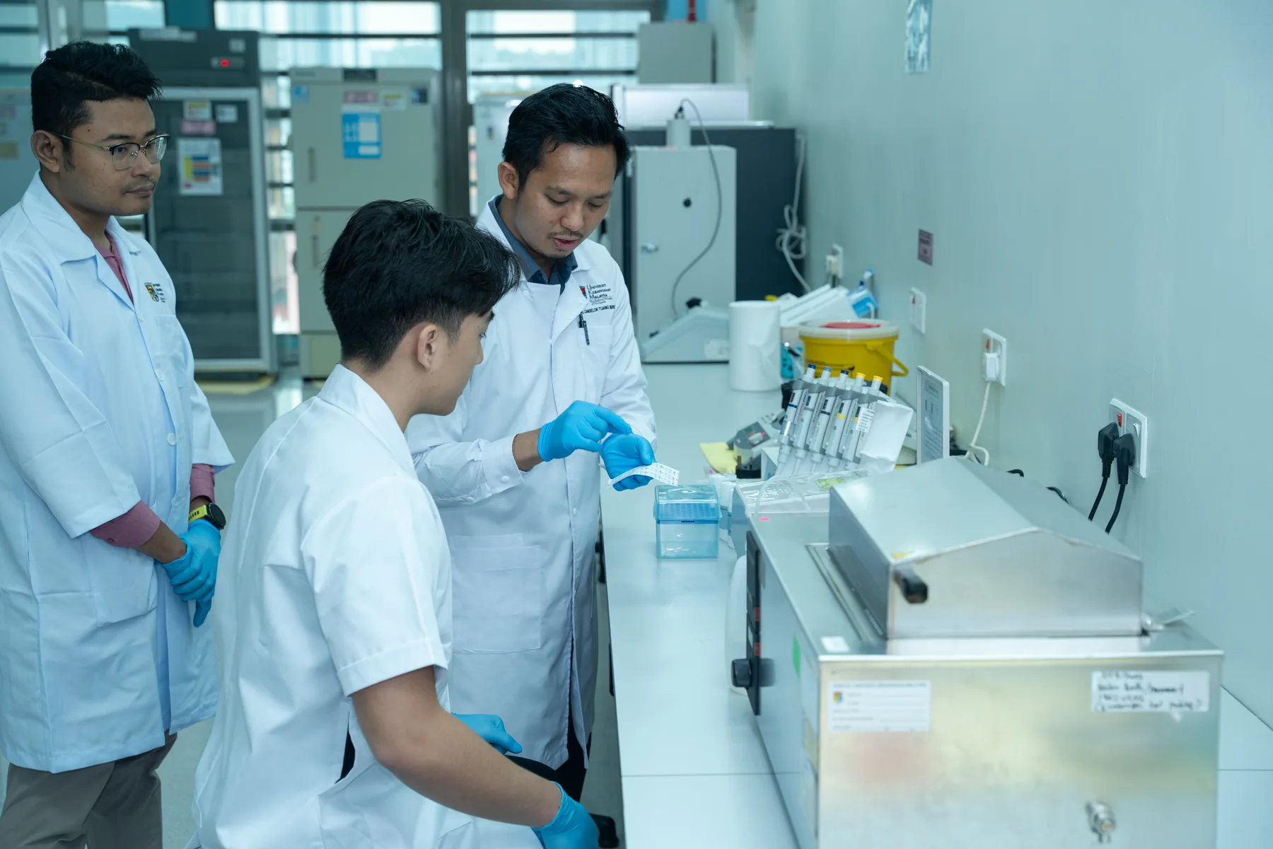 Louie and UKM researchers working together around laboratory equipment