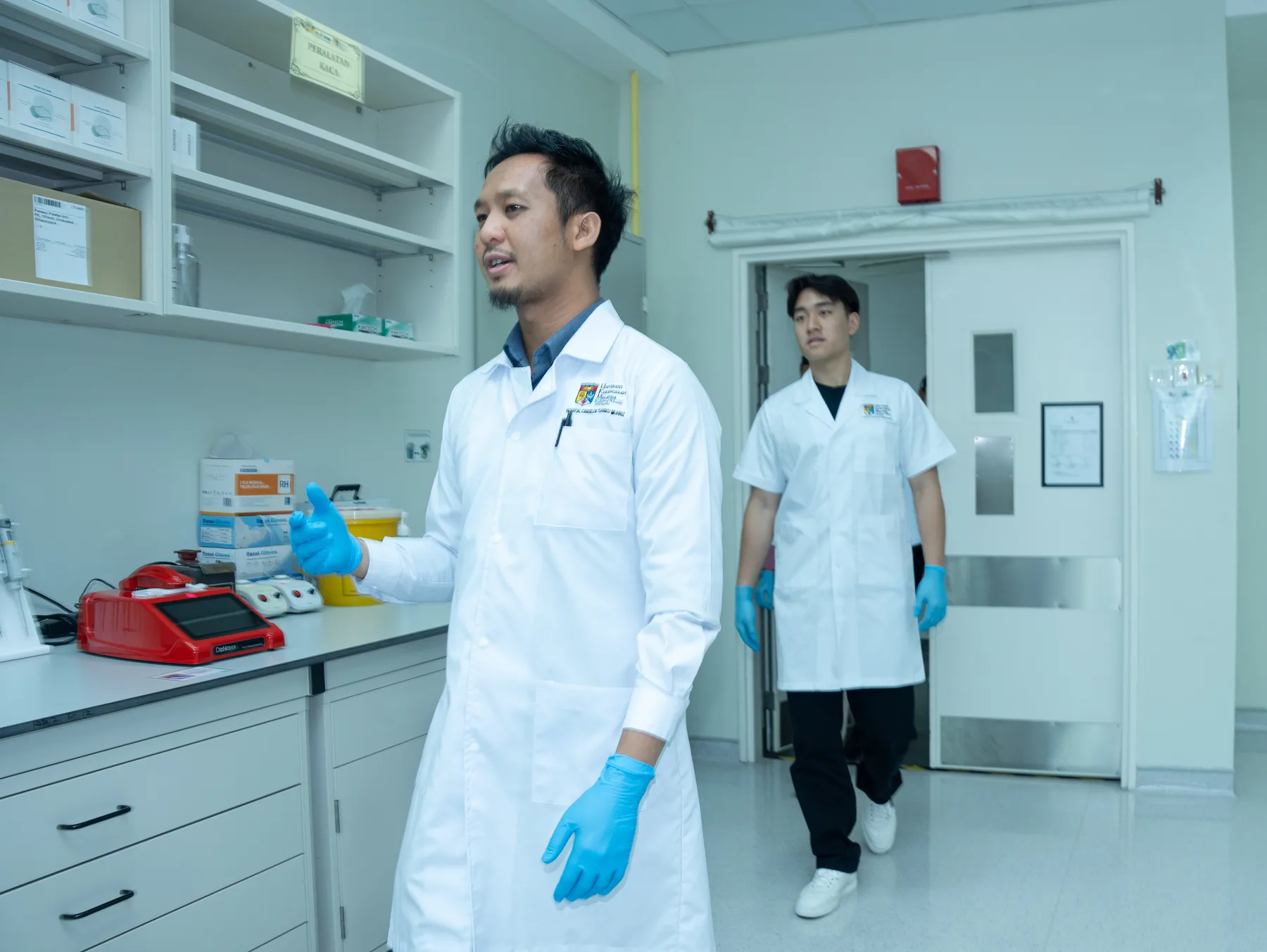 A UKM researcher demonstrating laboratory equipment while Louie observes
