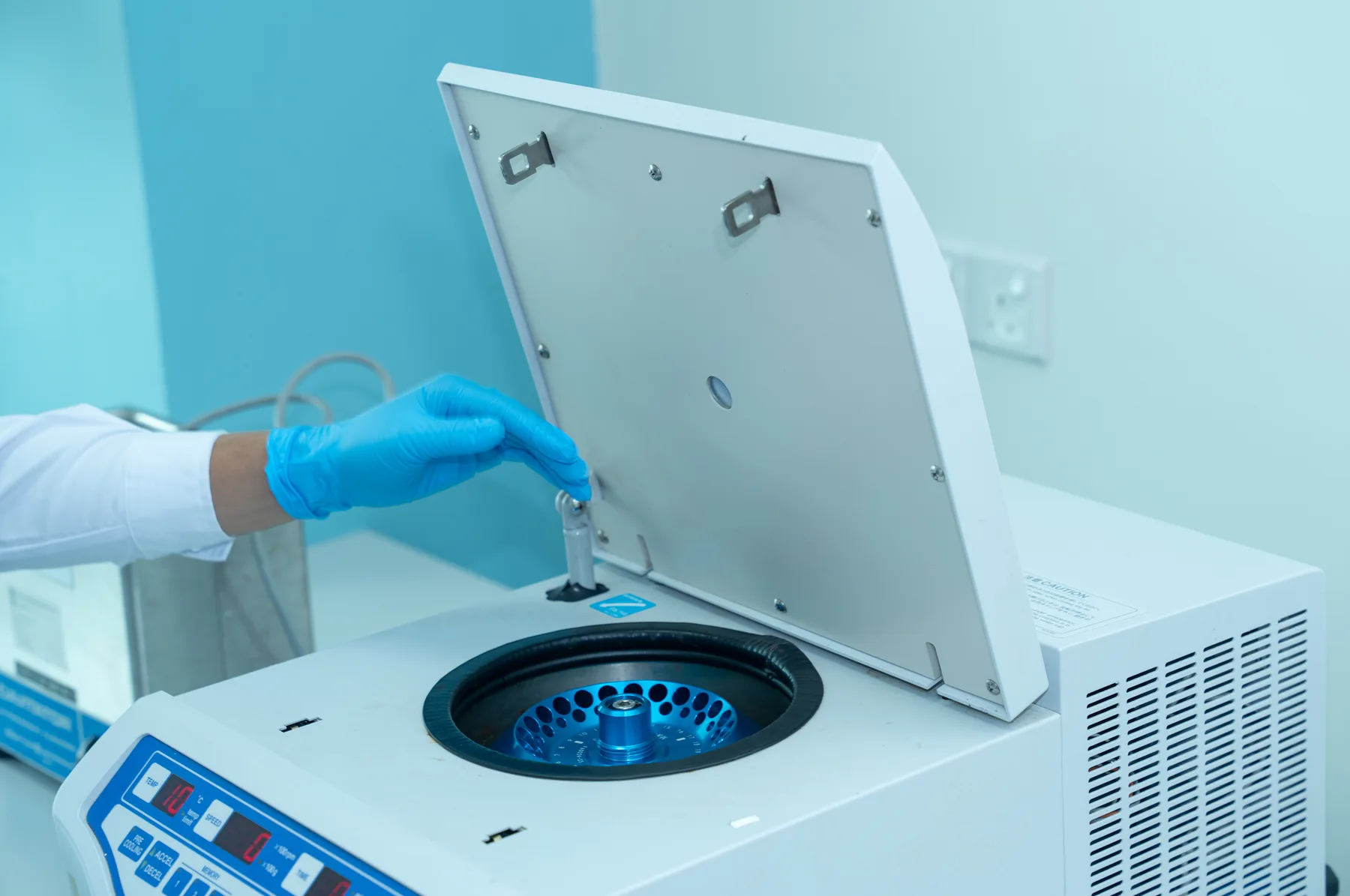 A gloved researcher placing samples into a laboratory centrifuge