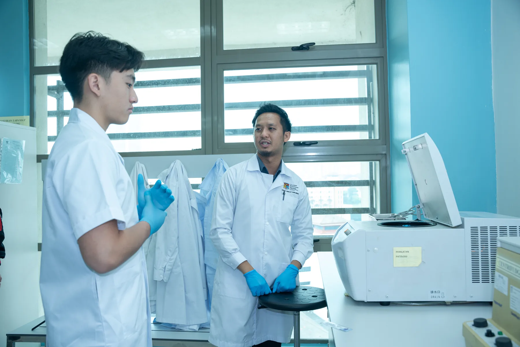 Louie discussing laboratory equipment with a UKM researcher