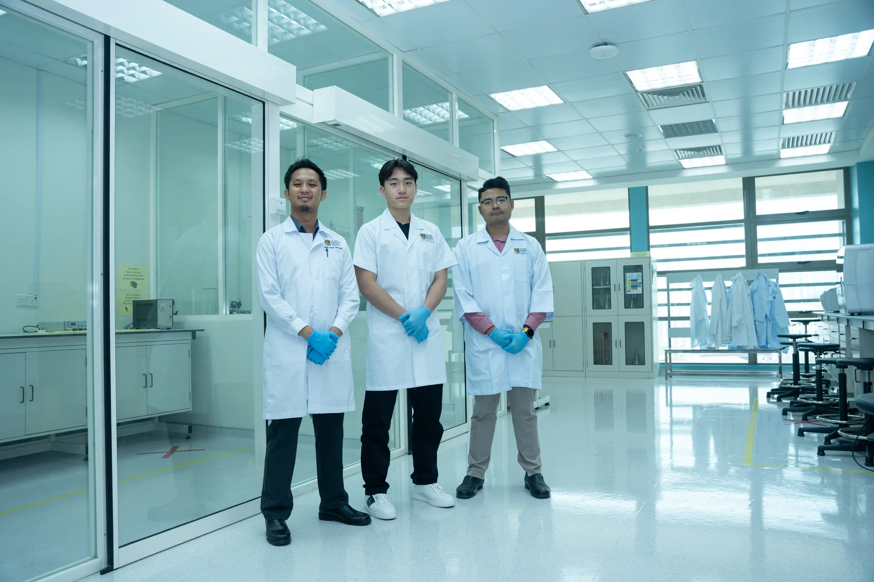 Louie walking through the UKM laboratory with two researchers