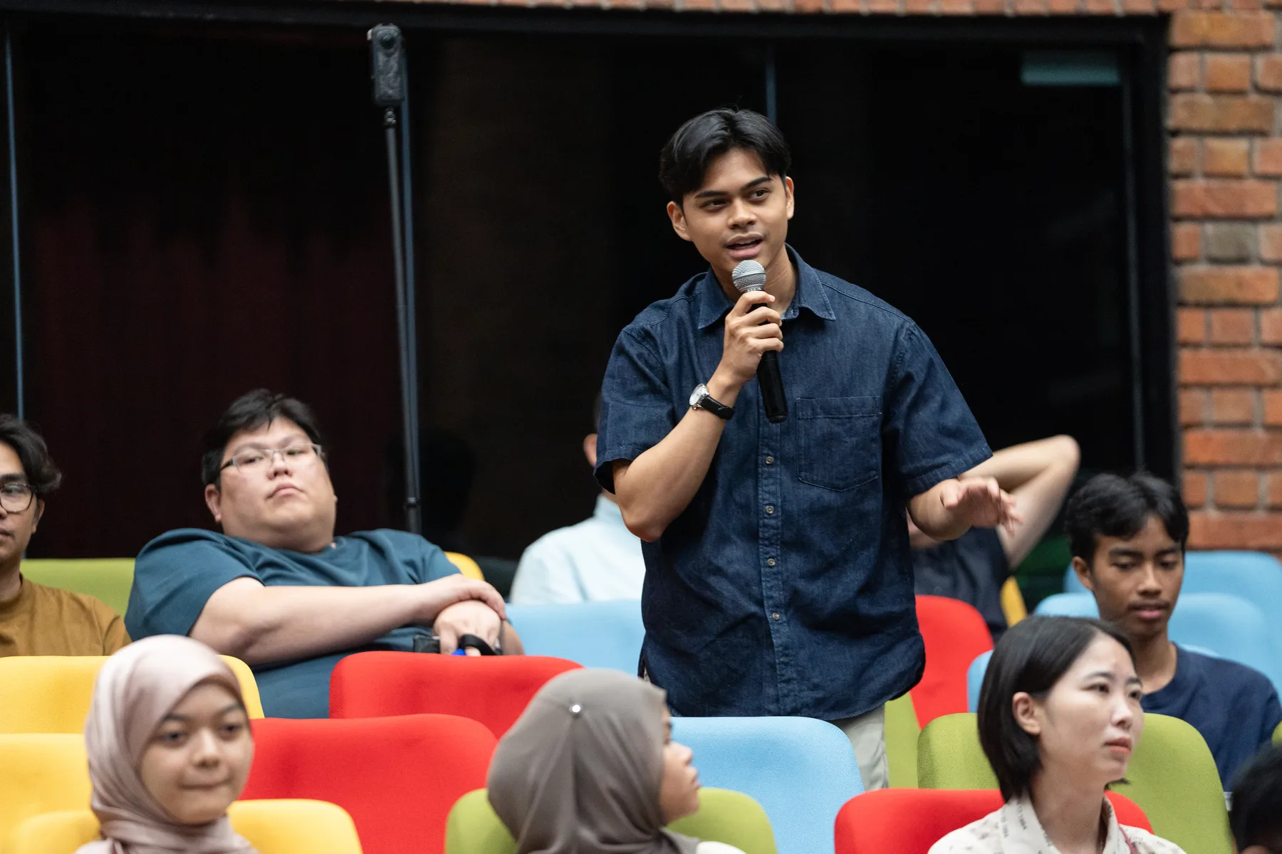 A young attendee speaking from the audience at UKM