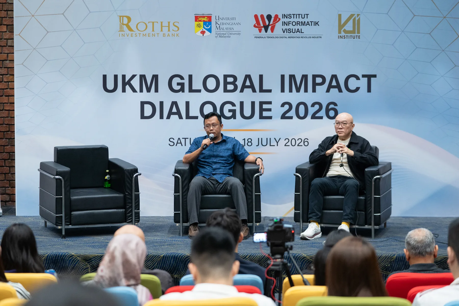 Panel guests discussing global impact before the UKM audience