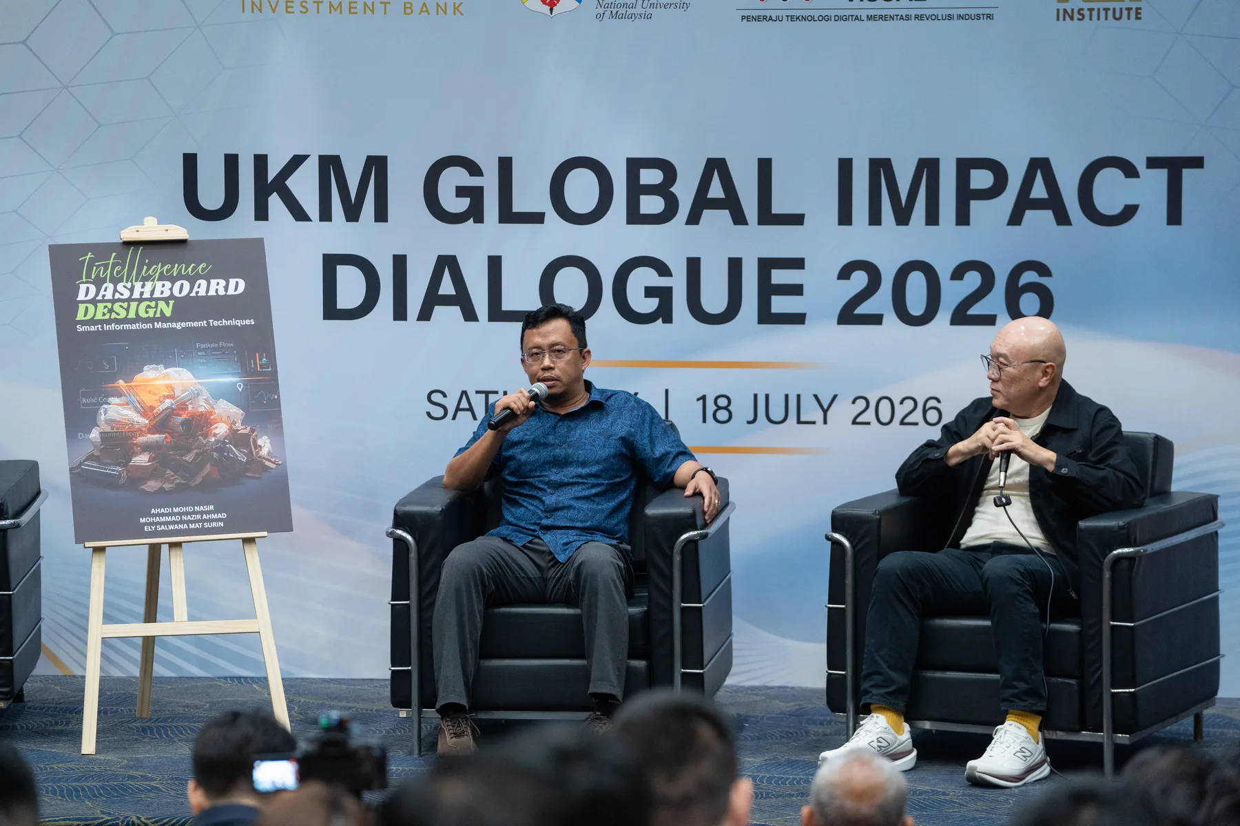 Two speakers discussing a leadership book during the UKM dialogue